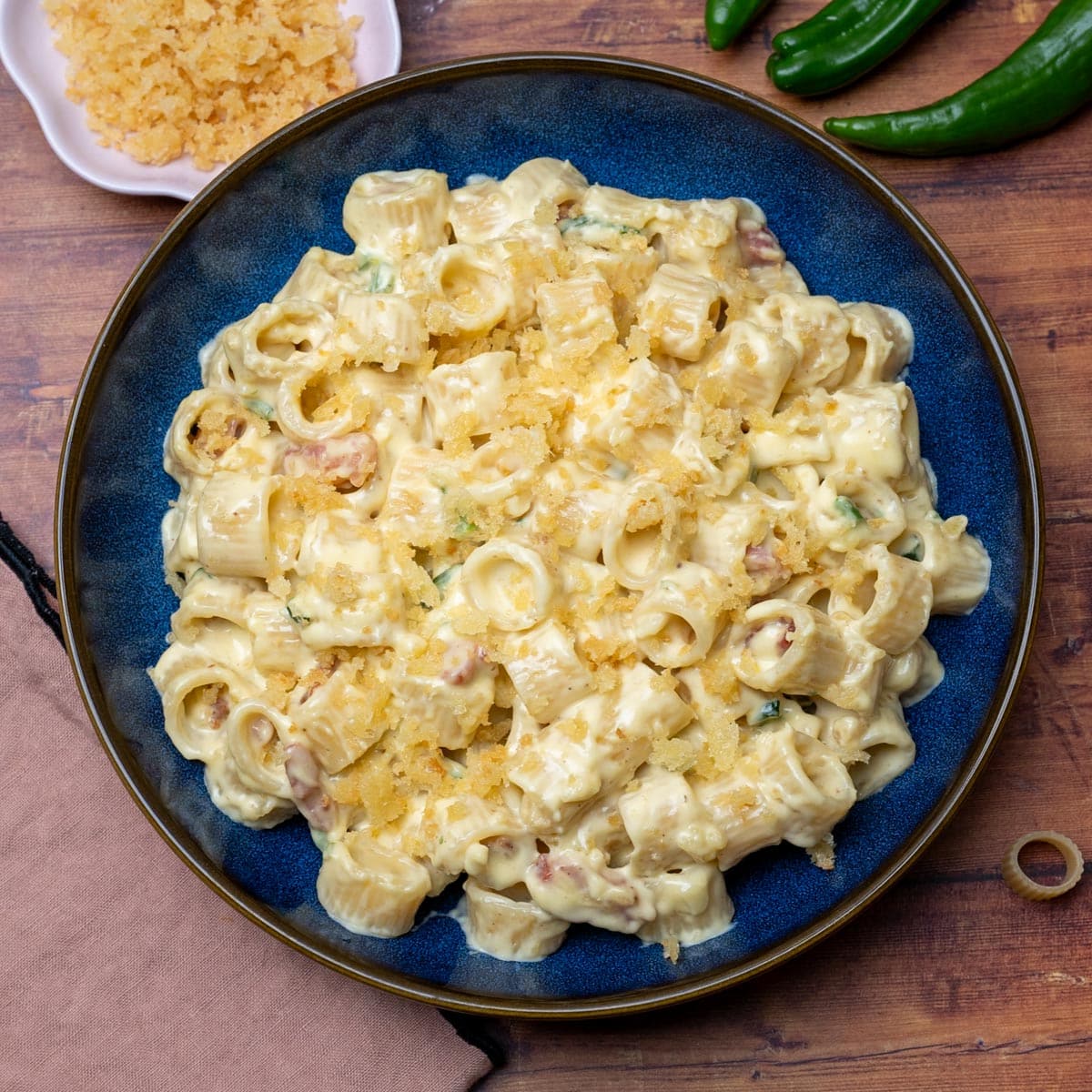 Easy jalapeño popper pasta plated in a dark bowl with all the toppings ready to serve