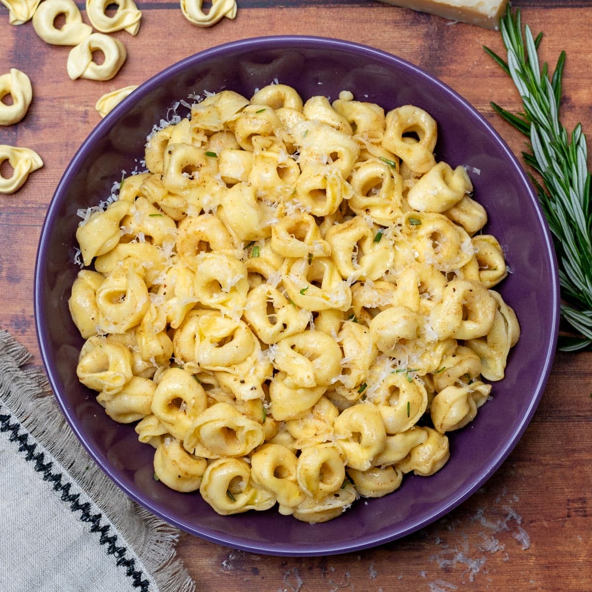 Easy brown butter tortellini in a purple bowl, finished with parmesan and fresh herbs